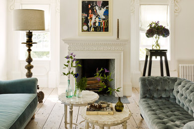 Example of a mid-sized classic formal and enclosed light wood floor and beige floor living room design in New York with white walls, a standard fireplace, a plaster fireplace and no tv
