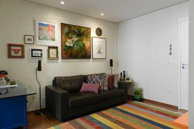 Diseño de salón con barra de bar abierto pequeño sin chimenea con paredes beige, suelo de madera en tonos medios y televisor colgado en la pared