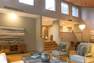 Foto de salón para visitas abierto actual grande sin chimenea y televisor con paredes púrpuras y suelo de madera en tonos medios