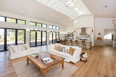 Modelo de salón abierto de estilo de casa de campo extra grande con paredes blancas, suelo de madera en tonos medios y suelo marrón
