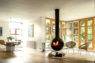 Idée de décoration pour un salon design ouvert avec une salle de réception, cheminée suspendue et un manteau de cheminée en bois.