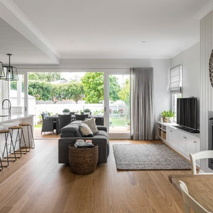 Transitional open concept living room in Brisbane with grey walls, medium hardwood floors, a standard fireplace, a freestanding tv and brown floor.