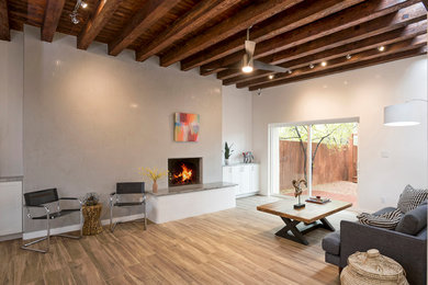 アルバカーキにある高級な小さなコンテンポラリースタイルのおしゃれなLDK (グレーの壁、磁器タイルの床、標準型暖炉、漆喰の暖炉まわり、茶色い床) の写真