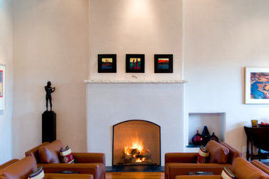 Repräsentatives, Fernseherloses, Großes, Offenes Mediterranes Wohnzimmer mit Kamin, weißer Wandfarbe, braunem Holzboden und verputzter Kaminumrandung in Albuquerque