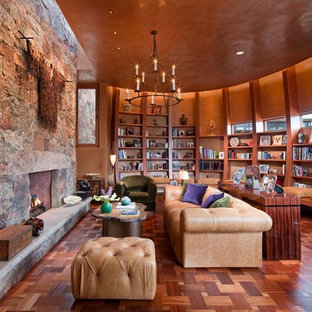 Geräumige, Fernseherlose, Abgetrennte Mediterrane Bibliothek mit oranger Wandfarbe, Kamin, dunklem Holzboden, Kaminumrandung aus Stein und braunem Boden in Albuquerque
