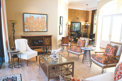 Diseño de salón abierto tradicional con paredes beige y suelo de madera clara