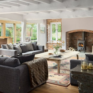 This is an example of a medium sized rural enclosed living room in Cheshire with beige walls, light hardwood flooring, a wood burning stove and beige floors.