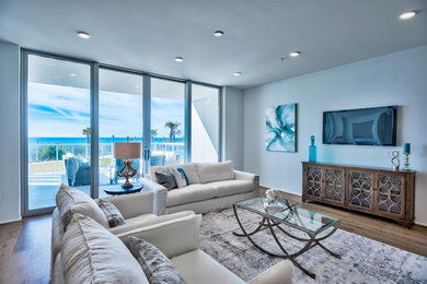 マイアミにある高級な広いビーチスタイルのおしゃれなLDK (白い壁、無垢フローリング、暖炉なし、壁掛け型テレビ、茶色い床) の写真