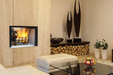 Diseño de salón moderno con paredes beige, suelo de madera clara, chimenea de doble cara y marco de chimenea de madera