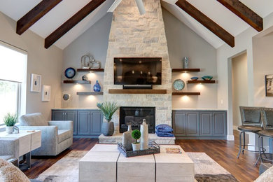 Example of a large transitional open concept medium tone wood floor and brown floor living room design in Dallas with gray walls, a standard fireplace, a stone fireplace and a wall-mounted tv