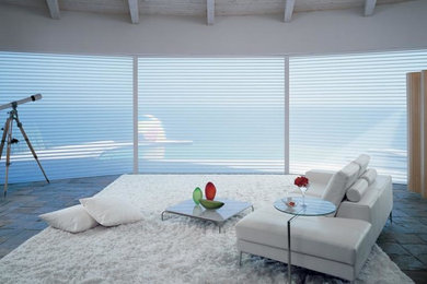 Diseño de salón abierto moderno grande sin chimenea con paredes blancas, suelo de pizarra y suelo gris
