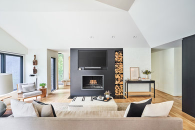 Modelo de salón actual con paredes negras, suelo de madera clara, todas las chimeneas, televisor colgado en la pared y suelo marrón