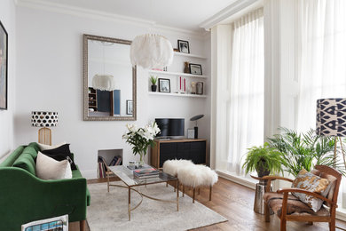 This is an example of a scandi living room with white walls, medium hardwood flooring, a freestanding tv and brown floors.