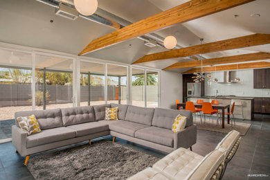 Example of a mid-sized mid-century modern open concept slate floor, black floor, vaulted ceiling and shiplap wall living room design in Phoenix with no fireplace and a wall-mounted tv