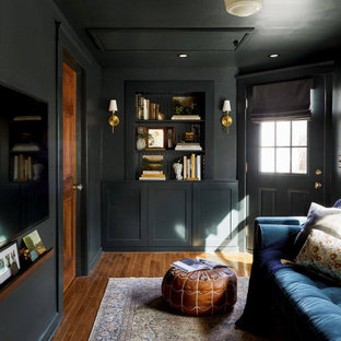 Example of a mid-sized transitional enclosed medium tone wood floor, brown floor and wainscoting living room library design in Detroit with black walls, no fireplace and a wall-mounted tv