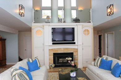 Пример оригинального дизайна: открытая гостиная комната среднего размера в морском стиле с синими стенами, светлым паркетным полом, фасадом камина из камня, телевизором на стене и стандартным камином