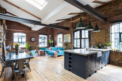 Inspiration for a large industrial open plan living room in London with brown floors and light hardwood flooring.