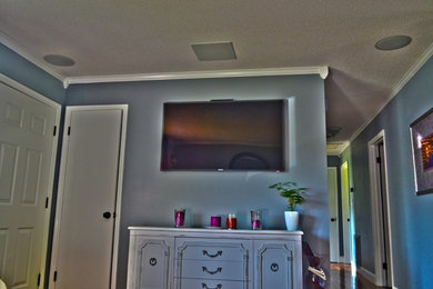 Ejemplo de salón abierto ecléctico de tamaño medio con paredes grises, suelo de madera en tonos medios y televisor colgado en la pared