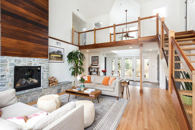 Example of a trendy formal and open concept medium tone wood floor living room design in Other with white walls, a standard fireplace and a stone fireplace