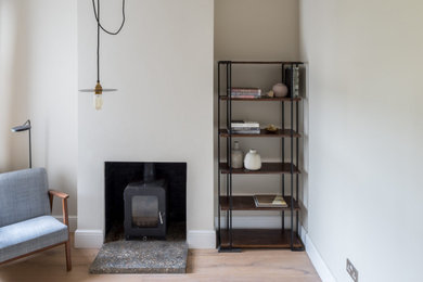Inspiration for a small scandi enclosed living room in Cardiff with a reading nook, beige walls, medium hardwood flooring, a wood burning stove and a plastered fireplace surround.