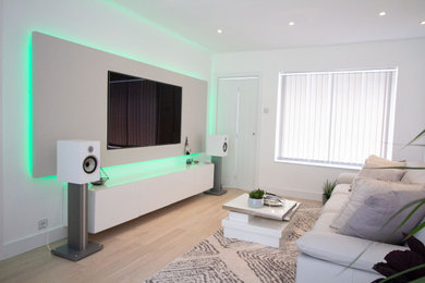 Exempel på ett litet modernt allrum med öppen planlösning, med ett finrum, vita väggar, ljust trägolv, en dold TV och beiget golv
