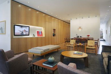 Modelo de salón minimalista de tamaño medio sin chimenea con pared multimedia, paredes blancas, suelo de madera en tonos medios y alfombra
