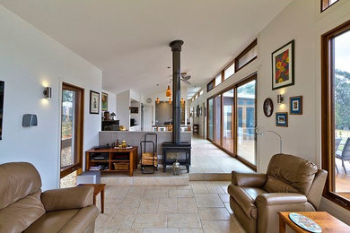 Foto de salón abierto actual de tamaño medio con estufa de leña, marco de chimenea de metal y suelo beige