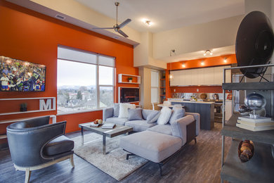 Diseño de salón abierto contemporáneo grande con parades naranjas, suelo de madera oscura y televisor colgado en la pared