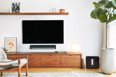 Modelo de salón para visitas actual sin chimenea con paredes blancas, suelo de madera clara, televisor colgado en la pared y suelo beige