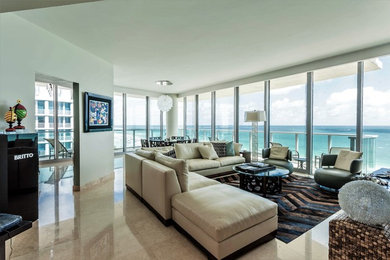 Example of a large trendy open concept travertine floor and beige floor living room design in Miami with white walls and a wall-mounted tv