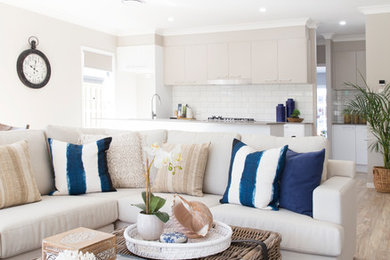 Large coastal open plan living room in Brisbane with white walls, vinyl flooring and brown floors.