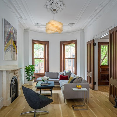 Example of a mid-sized transitional formal and enclosed medium tone wood floor and brown floor living room design in Boston with white walls, a standard fireplace, a stone fireplace and no tv