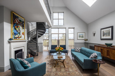 This is an example of a classic grey and teal living room in London with grey walls, medium hardwood flooring, a standard fireplace, a plastered fireplace surround and brown floors.