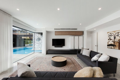 Modelo de salón cerrado moderno con paredes blancas, suelo de cemento, televisor colgado en la pared y suelo gris