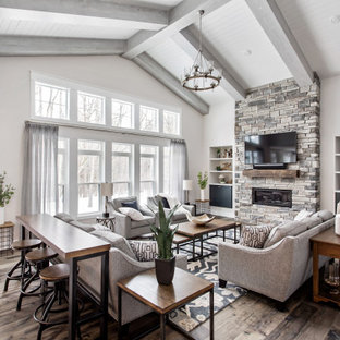 Inspiration for a country open concept dark wood floor, brown floor, exposed beam, shiplap ceiling and vaulted ceiling living room remodel in New York with gray walls, a ribbon fireplace, a stacked stone fireplace and a wall-mounted tv