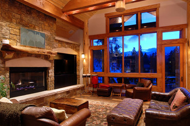Inspiration for a mid-sized rustic open concept medium tone wood floor living room remodel in Denver with beige walls, a standard fireplace, a stone fireplace and a media wall