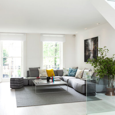 Example of a mid-sized trendy formal and open concept light wood floor living room design in London with white walls, a standard fireplace, a stone fireplace and no tv