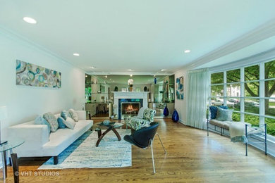 This is an example of a medium sized modern open plan living room in Chicago with white walls, light hardwood flooring, a standard fireplace, a stone fireplace surround and brown floors.