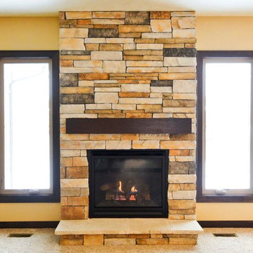 Stone fireplace in living room with wood mantel shelving