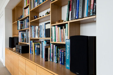 Immagine di un soggiorno minimal di medie dimensioni e chiuso con libreria, pareti bianche, moquette e pavimento beige