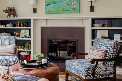 Cette image montre un grand salon traditionnel avec un mur beige, un sol en bois brun, une cheminée standard, un manteau de cheminée en pierre, aucun téléviseur et un sol marron.