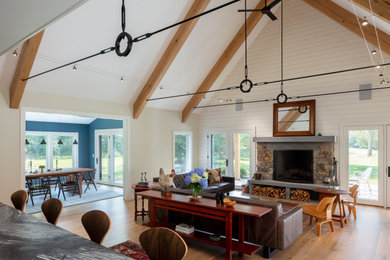 Example of a large country open concept light wood floor and brown floor living room design in Providence with white walls, a standard fireplace, a stone fireplace and no tv
