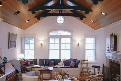 Example of an arts and crafts enclosed medium tone wood floor living room design in Portland Maine with white walls, a standard fireplace, a stone fireplace and no tv