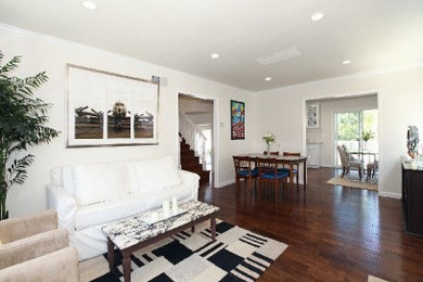 Elegant open concept dark wood floor living room photo in Los Angeles with white walls
