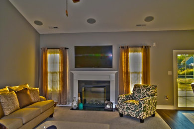 Offenes Klassisches Wohnzimmer mit grauer Wandfarbe, dunklem Holzboden, Kamin, Kaminumrandung aus Holz und TV-Wand in Sonstige