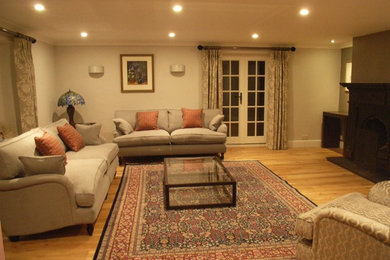 Imagen de salón clásico grande con paredes grises, suelo de madera clara y marco de chimenea de metal