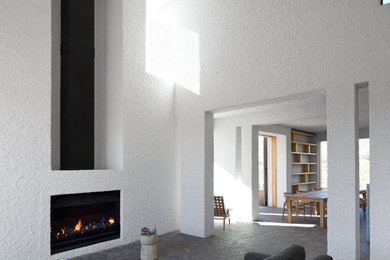 他の地域にあるコンテンポラリースタイルのおしゃれな応接間 (白い壁、レンガの床、標準型暖炉、漆喰の暖炉まわり) の写真
