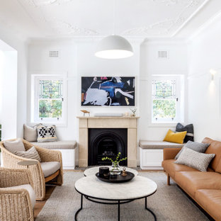 Photo of a transitional open concept living room in Sydney with white walls, medium hardwood floors, a standard fireplace and brown floor.