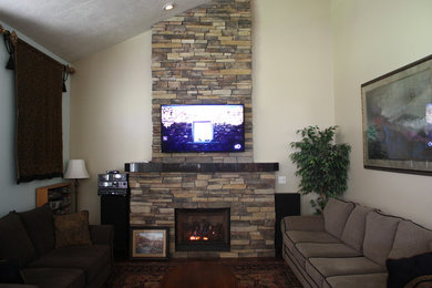 Diseño de salón tradicional con paredes beige, todas las chimeneas, marco de chimenea de piedra y televisor colgado en la pared