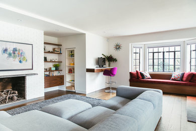Cette image montre un salon design ouvert avec un mur blanc, une cheminée standard, un manteau de cheminée en brique, un sol en bois brun et un sol marron.
